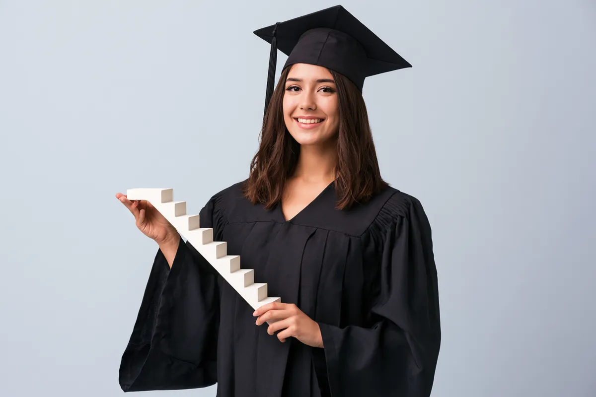Graduate holding a staircase model showing credit score rebuilding steps